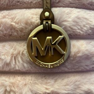 MK Michael Kors iconic Gold bag charm on a leather loop to attach to your purse.